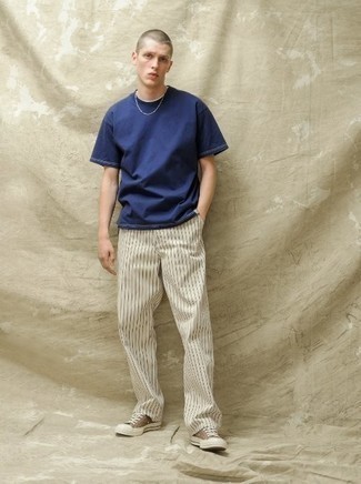 Brown Canvas Low Top Sneakers Outfits For Men: This pairing of a navy crew-neck t-shirt and white vertical striped chinos is the perfect foundation for a variety of getups. We're totally digging how complete this outfit looks when complemented by brown canvas low top sneakers.