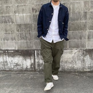 Men's Outfits 2021: This combination of a navy denim jacket and olive cargo pants makes for the perfect base for a casually cool outfit. Our favorite of a myriad of ways to complement this ensemble is with a pair of white canvas low top sneakers.