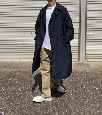 Navy Raincoat Outfits For Men: This cool and casual outfit is super simple: a navy raincoat and khaki chinos. Choose a pair of white canvas low top sneakers and the whole look will come together perfectly.