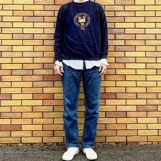 Navy and White Print Sweatshirt Outfits For Men: A navy and white print sweatshirt and blue jeans have cemented themselves as must-have wardrobe heroes. This ensemble is complemented nicely with white canvas low top sneakers.