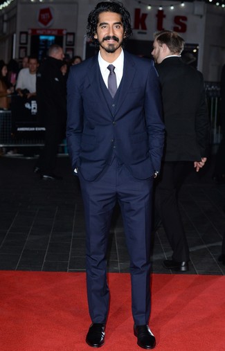 Dev Patel wearing Navy Three Piece Suit, White Dress Shirt, Black Leather Chelsea Boots, Navy Tie