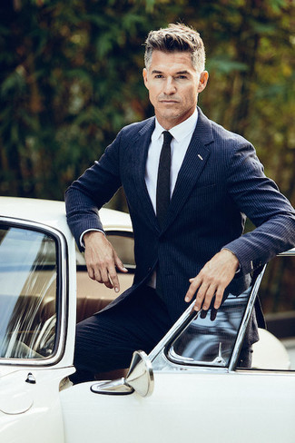 Black Tie Warm Weather Outfits For Men After 40: Loving how this pairing of a navy vertical striped suit and a black tie immediately makes you look sophisticated and stylish. This getup illustrates that slipping into your 40s is no reason to let your fashion standards drop.
