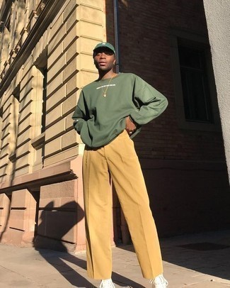 Green Baseball Cap Outfits For Men: This combo of an olive print long sleeve t-shirt and a green baseball cap is indisputable proof that a safe off-duty getup doesn't have to be boring. For something more on the elegant side to complement this look, complement your ensemble with white canvas high top sneakers.