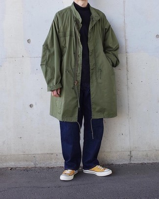 Dark Green Raincoat Outfits For Men: A dark green raincoat and navy jeans are totally worth adding to your list of veritable casual essentials. A pair of mustard canvas low top sneakers looks amazing complementing your outfit.