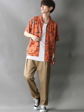 Mustard Print Short Sleeve Shirt Outfits For Men: The mix-and-match capabilities of a mustard print short sleeve shirt and khaki chinos guarantee they will be on heavy rotation in your wardrobe. Black and white canvas low top sneakers make this ensemble complete.
