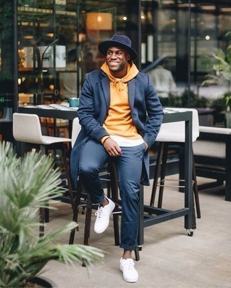 Orange Hoodie Outfits For Men: This off-duty pairing of an orange hoodie and navy chinos can take on different moods depending on how you style it. White canvas low top sneakers integrate well within a ton of getups.