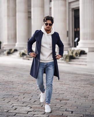 White Leather Low Top Sneakers Cold Weather Outfits For Men: Marry a navy overcoat with light blue skinny jeans if you seek to look cool and casual without spending too much time. A pair of white leather low top sneakers effortlessly turns up the wow factor of your look.