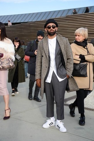 Grey Overcoat Outfits: A grey overcoat looks especially refined when worn with a charcoal vertical striped suit for an ensemble worthy of a British gentleman. Add white and black leather low top sneakers to the equation to easily amp up the appeal of this outfit.
