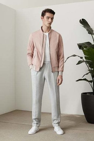 Pink Bomber Jacket Outfits For Men: This combination of a pink bomber jacket and grey chinos is extremely easy to create and so comfortable to wear a variation of all day long as well! A trendy pair of white canvas low top sneakers is an effortless way to bring a dash of stylish casualness to your look.