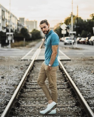 Light Blue Polo Outfits For Men: Flaunt your credentials in men's fashion by wearing this casual combo of a light blue polo and khaki chinos. White canvas low top sneakers are a wonderful pick to complement your ensemble.