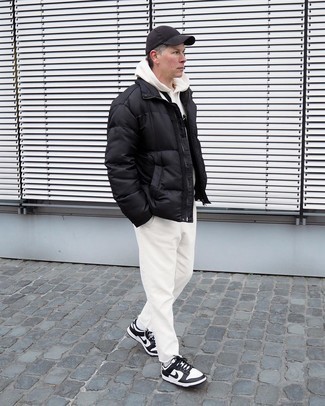White Leather Low Top Sneakers Cold Weather Outfits For Men: Go for a straightforward but polished option putting together a black puffer jacket and beige jeans. Our favorite of an infinite number of ways to complement this look is a pair of white leather low top sneakers.
