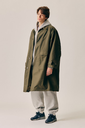 121 Relaxed Outfits For Men: An olive raincoat and grey sweatpants paired together are the perfect look for those who love casual combos. To bring a fun touch to your ensemble, introduce a pair of navy and white athletic shoes to this ensemble.