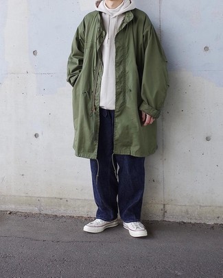 Olive Raincoat Outfits For Men: Breathe variety into your day-to-day off-duty repertoire with an olive raincoat and navy jeans. If you're not sure how to finish off, a pair of white canvas low top sneakers is a wonderful option.
