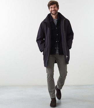 Black Raincoat Outfits For Men: A black raincoat and grey chinos married together are a sartorial dream for gents who prefer laid-back and cool getups. If you want to immediately dial up this getup with one piece, why not add dark brown suede chelsea boots to the mix?