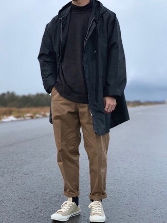 Black Raincoat Outfits For Men: This laid-back pairing of a black raincoat and brown chinos is a never-failing option when you need to look good but have no extra time. Complement this ensemble with beige canvas low top sneakers and ta-da: your look is complete.