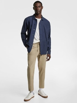 Navy Shirt Jacket Warm Weather Outfits For Men: This smart casual pairing of a navy shirt jacket and khaki chinos is super easy to throw together without a second thought, helping you look sharp and prepared for anything without spending a ton of time rummaging through your wardrobe. Finishing with white leather low top sneakers is a guaranteed way to infuse a more relaxed spin into your getup.