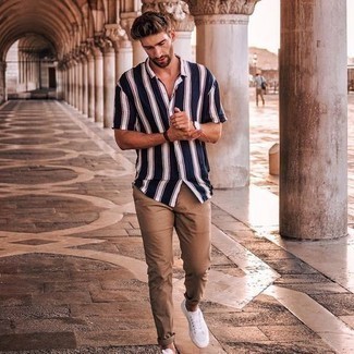 Navy Vertical Striped Short Sleeve Shirt Outfits For Men: This combo of a navy vertical striped short sleeve shirt and khaki chinos is simple, sharp and very easy to copy. All you need is a pair of white canvas low top sneakers.