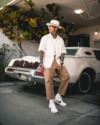 White Straw Hat Outfits For Men: Putting together a beige short sleeve shirt and a white straw hat will cement your prowess in menswear styling even on lazy days. Let your styling expertise truly shine by completing this look with white and black canvas low top sneakers.