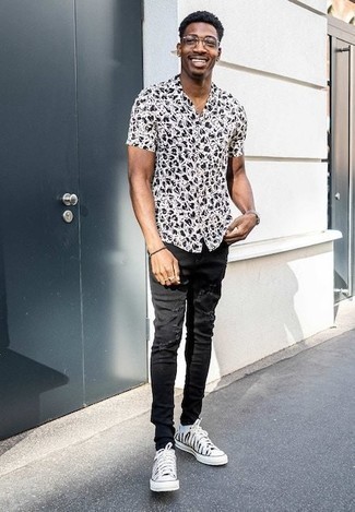 White Print Canvas Low Top Sneakers Outfits For Men: A white and black print short sleeve shirt and black ripped jeans are a good getup to keep in your off-duty collection. Finishing with white print canvas low top sneakers is a simple way to add some extra depth to this getup.