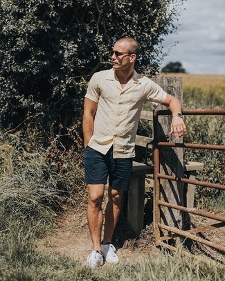 Tan Leather Watch Outfits For Men: If you like the comfort look, marry a beige vertical striped short sleeve shirt with a tan leather watch. Let your styling chops really shine by finishing off your look with white and black canvas low top sneakers.