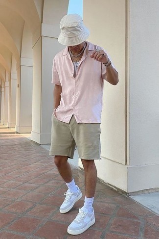 Beige Sports Shorts Outfits For Men: We're all looking for functionality when it comes to styling, and this edgy combo of a pink short sleeve shirt and beige sports shorts is a practical illustration of that. You could perhaps get a bit experimental on the shoe front and class up this getup by wearing white leather low top sneakers.