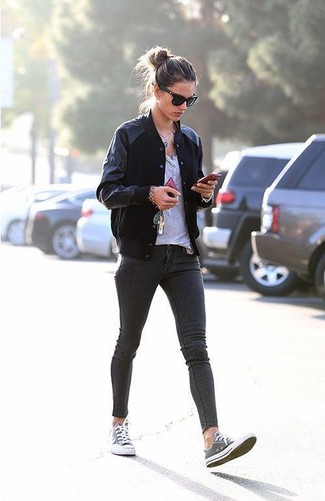 Alessandra Ambrosio wearing Grey Canvas Low Top Sneakers, Charcoal Skinny Jeans, Grey Henley Shirt, Black Varsity Jacket