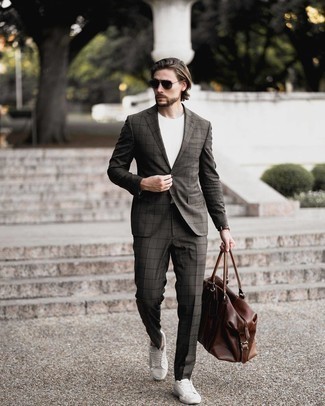 Brown Duffle Bag Outfits For Men: Make a charcoal check suit and a brown duffle bag your outfit choice for a casual kind of sophistication. Complement your look with a pair of white canvas low top sneakers and ta-da: the look is complete.