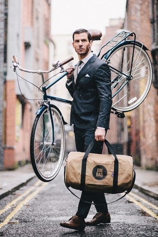 Beige Canvas Duffle Bag Outfits For Men: This combination of a charcoal suit and a beige canvas duffle bag is on the casual side yet it's also sharp and seriously dapper. For something more on the dressier end to complete your getup, add dark brown leather derby shoes to this outfit.
