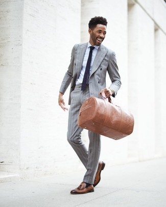 Tan Leather Holdall Outfits For Men: Make a grey vertical striped suit and a tan leather holdall your outfit choice for a standout ensemble. To introduce an extra dimension to this ensemble, complete this getup with brown leather tassel loafers.