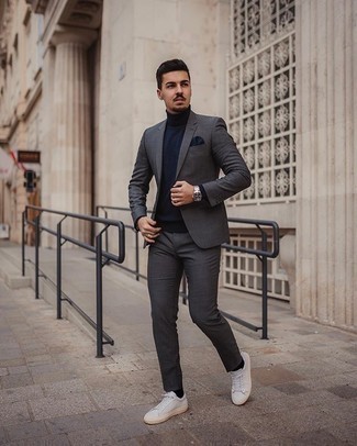 Charcoal Suit Outfits In Their 20s: This combination of a charcoal suit and a navy turtleneck is the definition of manly sophistication. White canvas low top sneakers are guaranteed to bring a dose of stylish effortlessness to this ensemble. So if you're in search of a nice yet mature pairing for a guy in his 20s, this one is great.