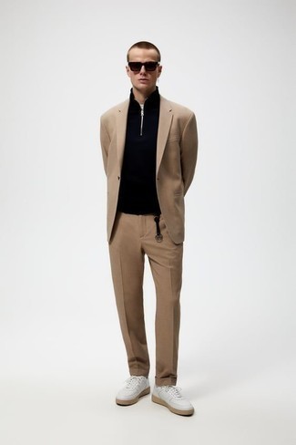 Tan Suit Outfits: This pairing of a tan suit and a black zip neck sweater can only be described as ridiculously sharp and classy. White leather low top sneakers will easily play down a polished getup.