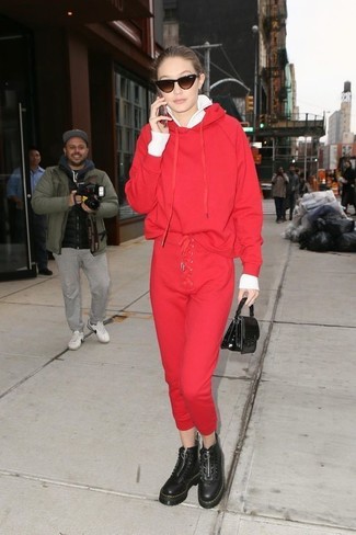 Gigi Hadid wearing Black Chunky Leather Lace-up Flat Boots, Red Sweatpants, Red Hoodie, White Zip Sweater