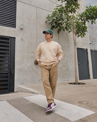 Baseball Cap Outfits For Men: If you put comfort above all else, this edgy combination of a beige sweatshirt and a baseball cap is your go-to. Not sure how to complete this look? Round off with a pair of dark purple leather low top sneakers to dial it up a notch.