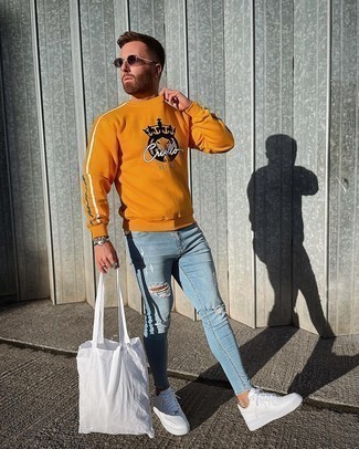 Men's Orange Print Sweatshirt, Light Blue Ripped Skinny Jeans, White Leather Low Top Sneakers, White Canvas Tote Bag