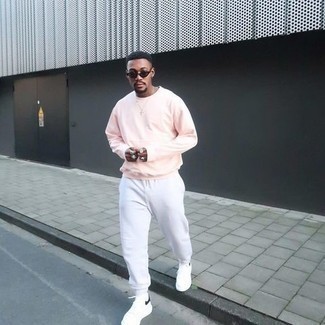 White Sweatpants Outfits For Men: Wear a pink sweatshirt with white sweatpants for a modern take on day-to-day menswear. A pair of white and black leather low top sneakers will be the ideal companion for your getup.