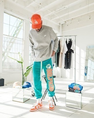 Orange Baseball Cap Outfits For Men: Sporting something as straightforward as this street style combination of a grey sweatshirt and an orange baseball cap can actually help you stand out. Introduce orange leather low top sneakers to this ensemble to instantly up the style factor of any getup.