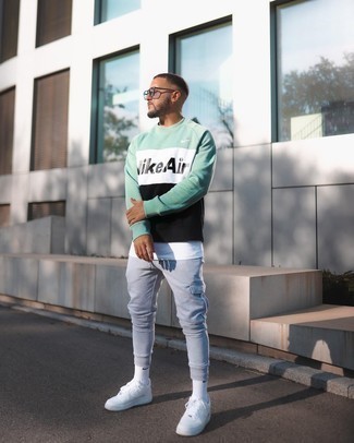 Green Sweatshirt Outfits For Men: Wear a green sweatshirt with grey cargo pants to pull together a cool and casual ensemble. A pair of white canvas low top sneakers acts as the glue that will tie your getup together.