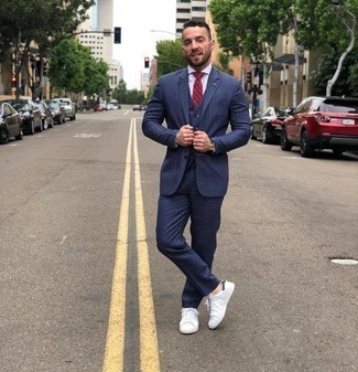 Navy Vertical Striped Three Piece Suit Outfits: Marrying a navy vertical striped three piece suit with a white dress shirt is a great pick for a sharp and elegant outfit. To give your getup a more laid-back touch, complement this outfit with white and navy leather low top sneakers.