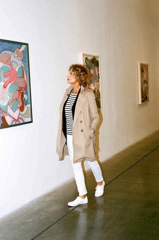 Lauren Hutton wearing Beige Trenchcoat, White and Black Horizontal Striped Long Sleeve T-shirt, White Jeans, White Canvas Low Top Sneakers