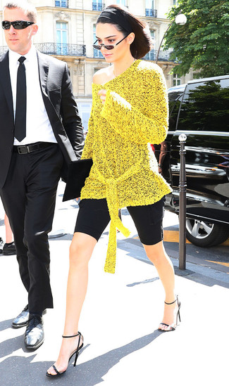 Kendall Jenner wearing Yellow Knit Tunic, Black Bike Shorts, Black Leather Heeled Sandals, Black Suede Clutch