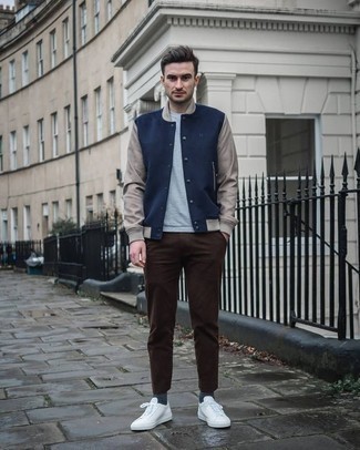 Navy Varsity Jacket Outfits For Men: Prove everyone that you know a thing or two about menswear in a navy varsity jacket and dark brown chinos. Introduce a pair of white canvas low top sneakers to the mix and the whole outfit will come together really well.