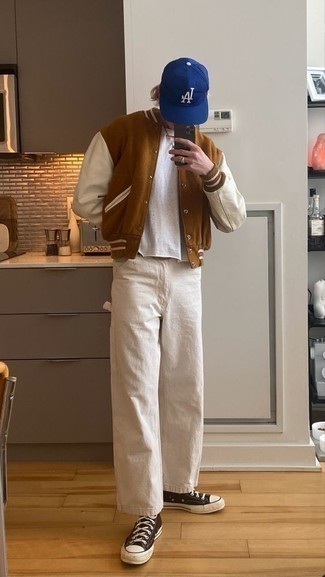 Beige Jeans Outfits For Men: A brown varsity jacket and beige jeans have become a go-to pairing for many stylish guys. For a more laid-back finish, why not complete your look with dark brown canvas high top sneakers?