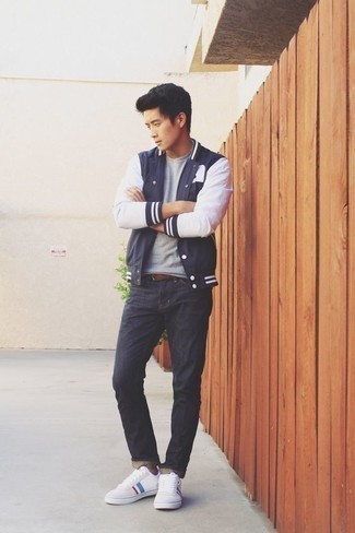 Varsity Jacket Casual Outfits For Men: Wear a varsity jacket with navy jeans for both stylish and easy-to-achieve outfit. Complement this getup with a pair of white print canvas low top sneakers for extra style points.