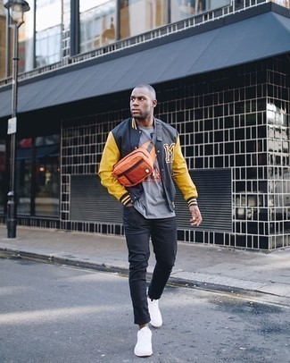 Orange Canvas Fanny Pack Outfits For Men: This dapper look is really pared down: a black print varsity jacket and an orange canvas fanny pack. Go ahead and introduce a pair of white canvas low top sneakers to the equation for an extra dose of elegance.