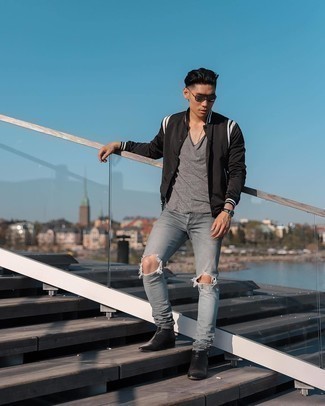Grey Ripped Jeans Outfits For Men: This relaxed casual pairing of a black and white varsity jacket and grey ripped jeans is a fail-safe option when you need to look dapper but have zero time. A cool pair of black leather chelsea boots is an easy way to breathe a hint of elegance into your ensemble.