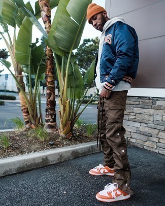 Orange Leather Low Top Sneakers Outfits For Men: This casual combination of a navy varsity jacket and dark brown cargo pants is a winning option when you need to look cool but have zero time to spare. Complement this ensemble with orange leather low top sneakers for extra style points.