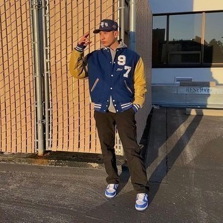 Navy Print Varsity Jacket Outfits For Men: If you gravitate towards casual combinations, why not wear a navy print varsity jacket with dark brown chinos? Let your sartorial prowess truly shine by completing your outfit with a pair of white and blue leather low top sneakers.