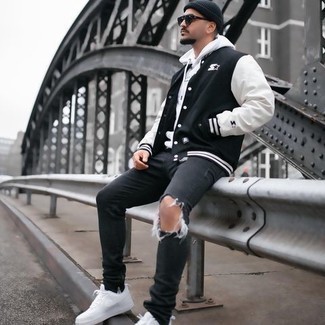 Black and White Varsity Jacket Outfits For Men: You're looking at the indisputable proof that a black and white varsity jacket and charcoal ripped jeans are amazing when teamed together in a contemporary ensemble. Wondering how to finish off your look? Finish off with white canvas low top sneakers to elevate it.