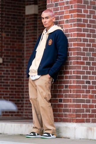 Navy Varsity Jacket Outfits For Men: Fashionable and comfortable, this casual pairing of a navy varsity jacket and khaki chinos provides with endless styling opportunities. White and black leather low top sneakers look perfectly at home here.