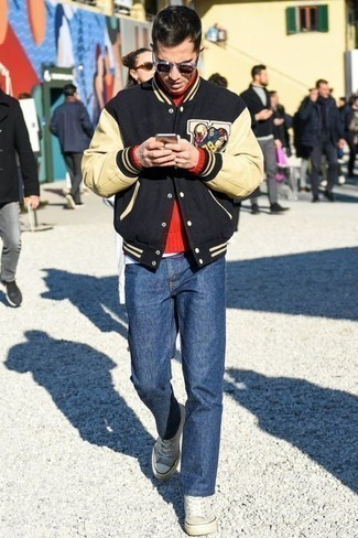 Men's Outfits 2022: A black print varsity jacket and navy jeans are a savvy combination worth integrating into your casual styling routine. A pair of grey canvas low top sneakers integrates really well within a ton of ensembles.